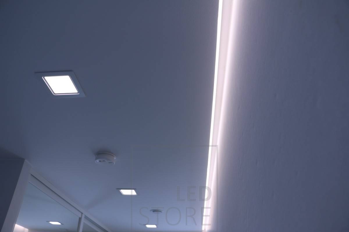 Indirekte Beleuchtung an der Deckenbegrenzung kombiniert mit Allgemeinbeleuchtung mit Panel-Leuchten. Ledstore.fi