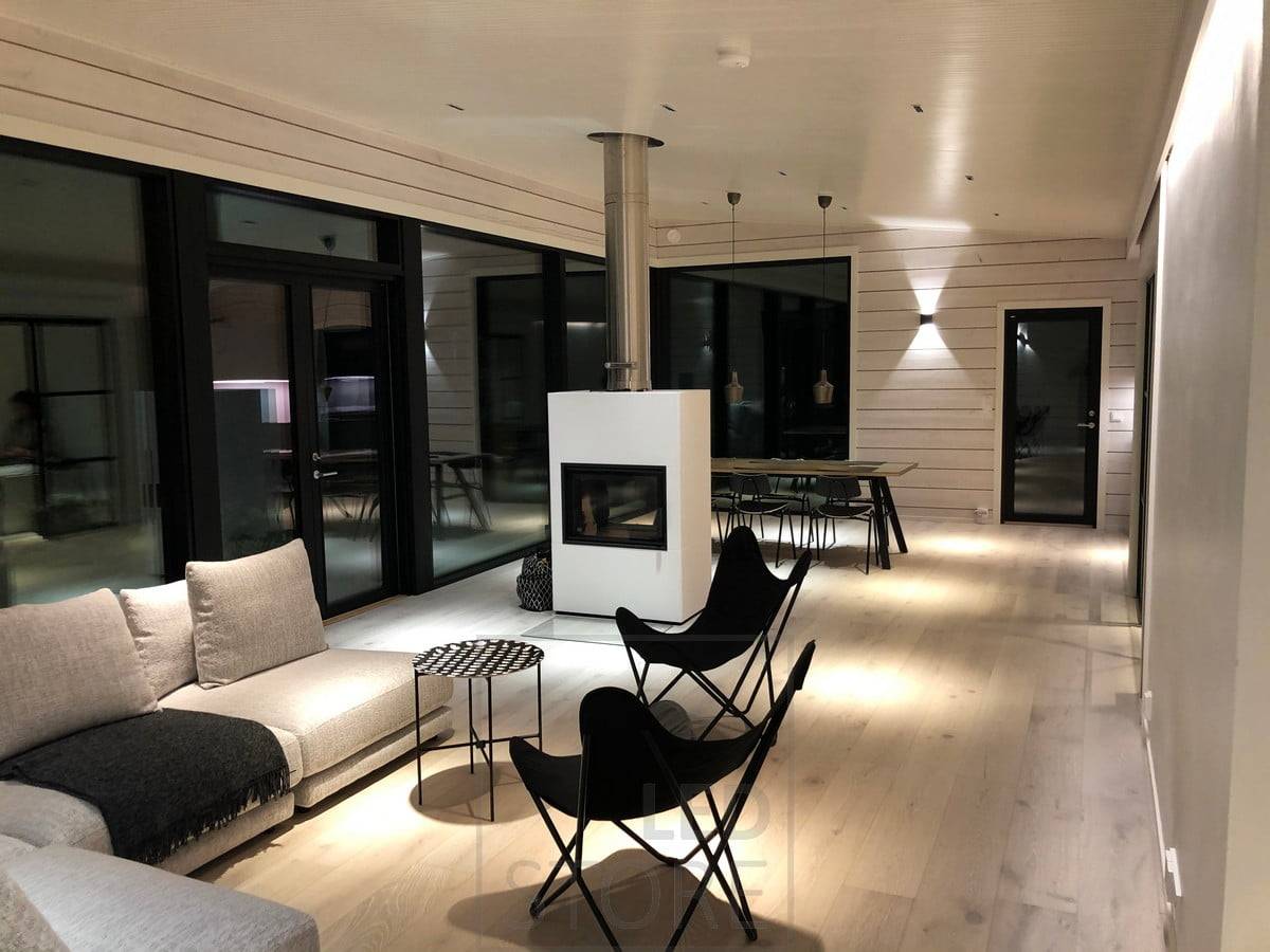 Schwarze FUNK Wandleuchte im Wohnzimmer als Stimmungslicht. Die Leuchte ist minimalistisch, modern und perfekt für skandinavische Innenräume. Ledstore.fi
