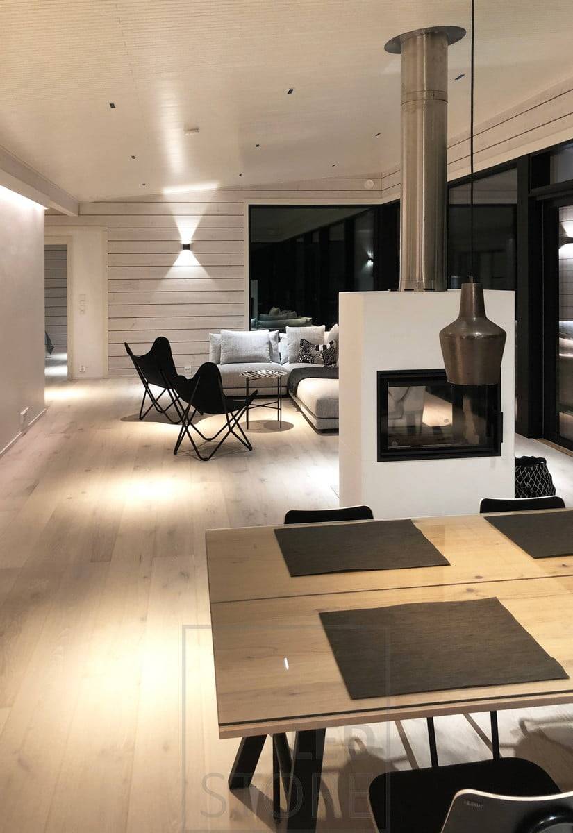Die schwarze FUNK Wandleuchte erhellt das Wohnzimmer mit stimmungsvollem Licht durch die Wand. Als Allgemeinbeleuchtung im Raum beleuchten LINJA 2 Strahler das nischenartige Licht. Ledstore.fi