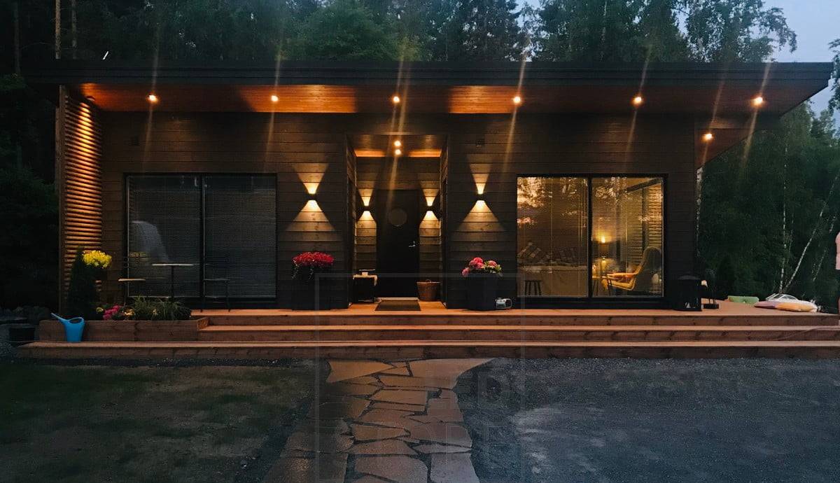 Schwarze FUNK-Wandleuchten an der Gebäudewand, die die Fassade beleuchten und eine stimmungsvolle Außenbeleuchtung schaffen. FUNK LED-Wandleuchten haben einen einstellbaren Öffnungswinkel nach Ihren Bedürfnissen. Die Leuchte ist auch dimmbar. Ledstore.fi