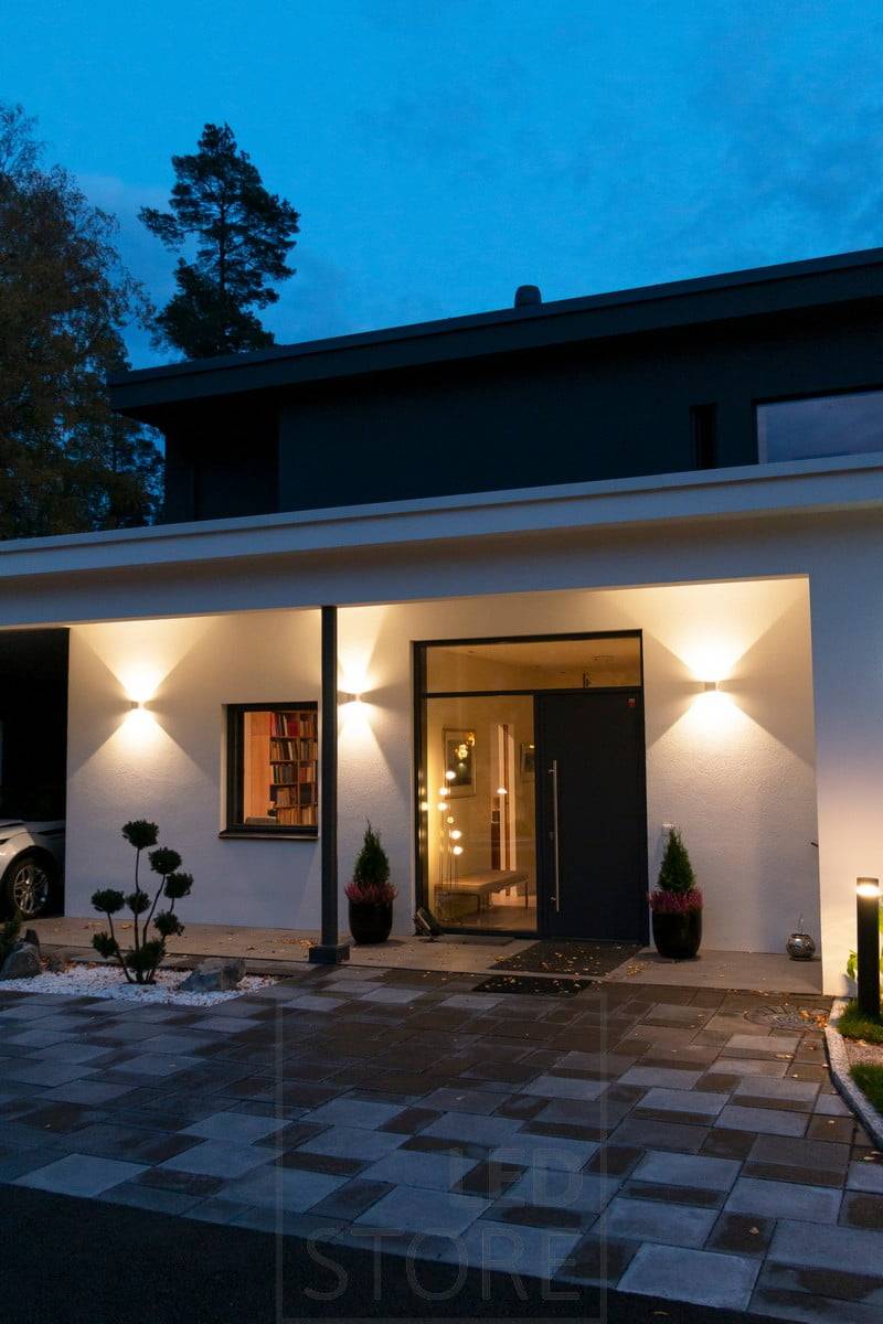 Weiße FUNK-Wandleuchten an der Gebäudewand, die die Fassade beleuchten und eine stimmungsvolle Außenbeleuchtung schaffen. Ledstore.fi