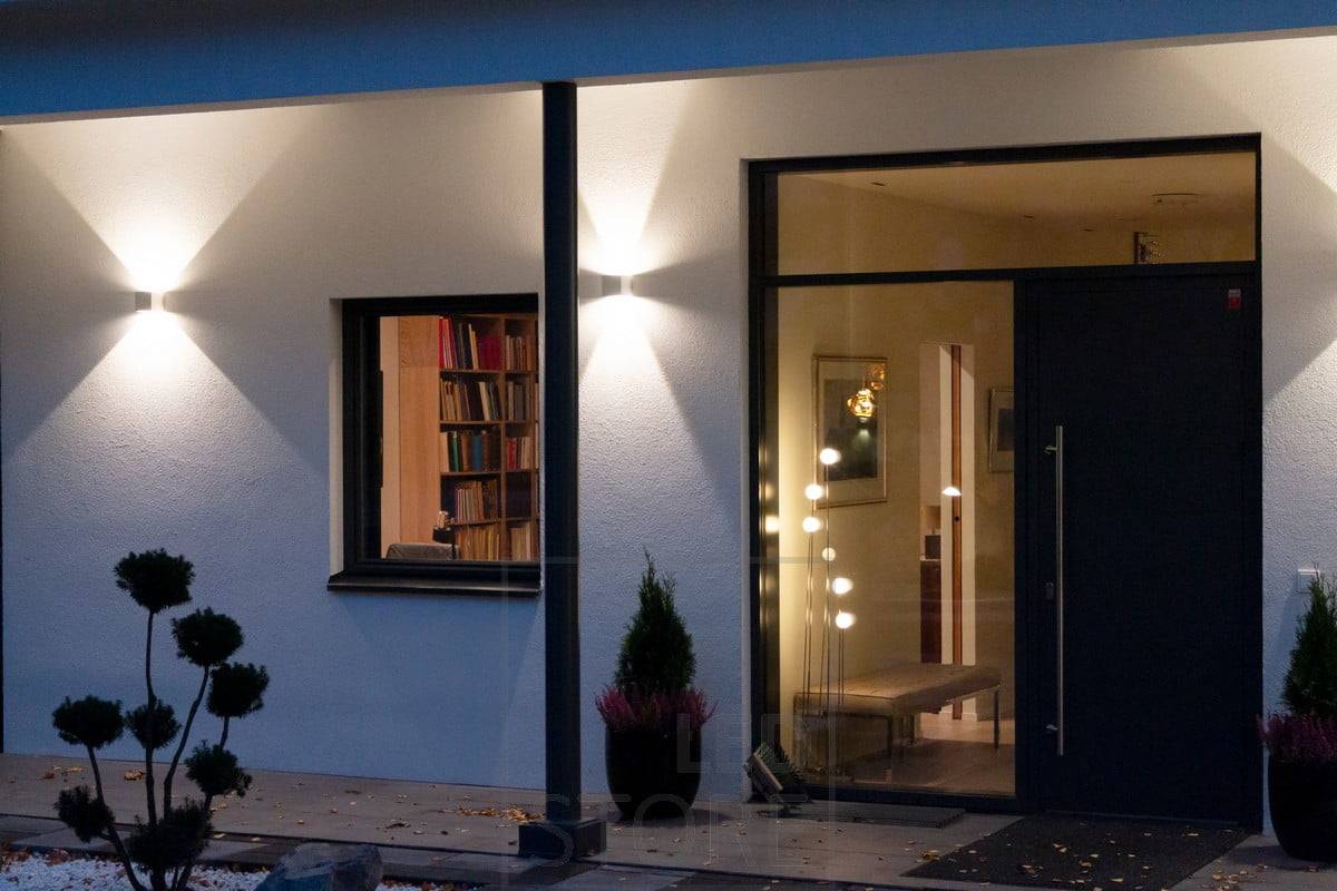 Weiße FUNK-Wandleuchten an der Gebäudewand, die die Fassade beleuchten und eine stimmungsvolle Außenbeleuchtung schaffen. Der Winkel, in dem sich das Licht öffnet, ist einstellbar. Ledstore.fi