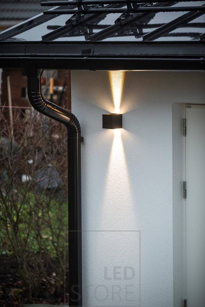 Schwarze, bidirektionale FUNK LED-Wandleuchten, die die Fassade der Garage beleuchten. Das nach oben gerichtete Licht endet an der Traufe. Ledstore.fi