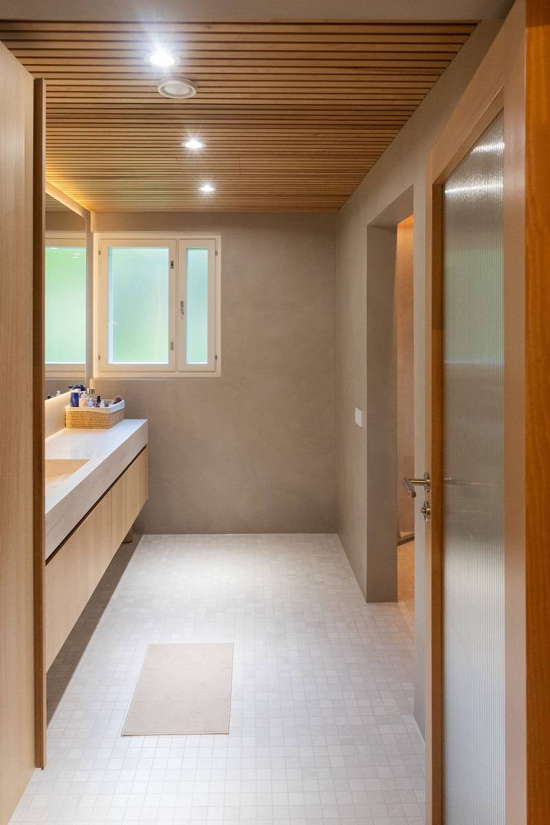 Spotlights und ein LED-Streifen hinter dem Spiegel beleuchten den Bereich vor dem Waschbecken im Badezimmer.