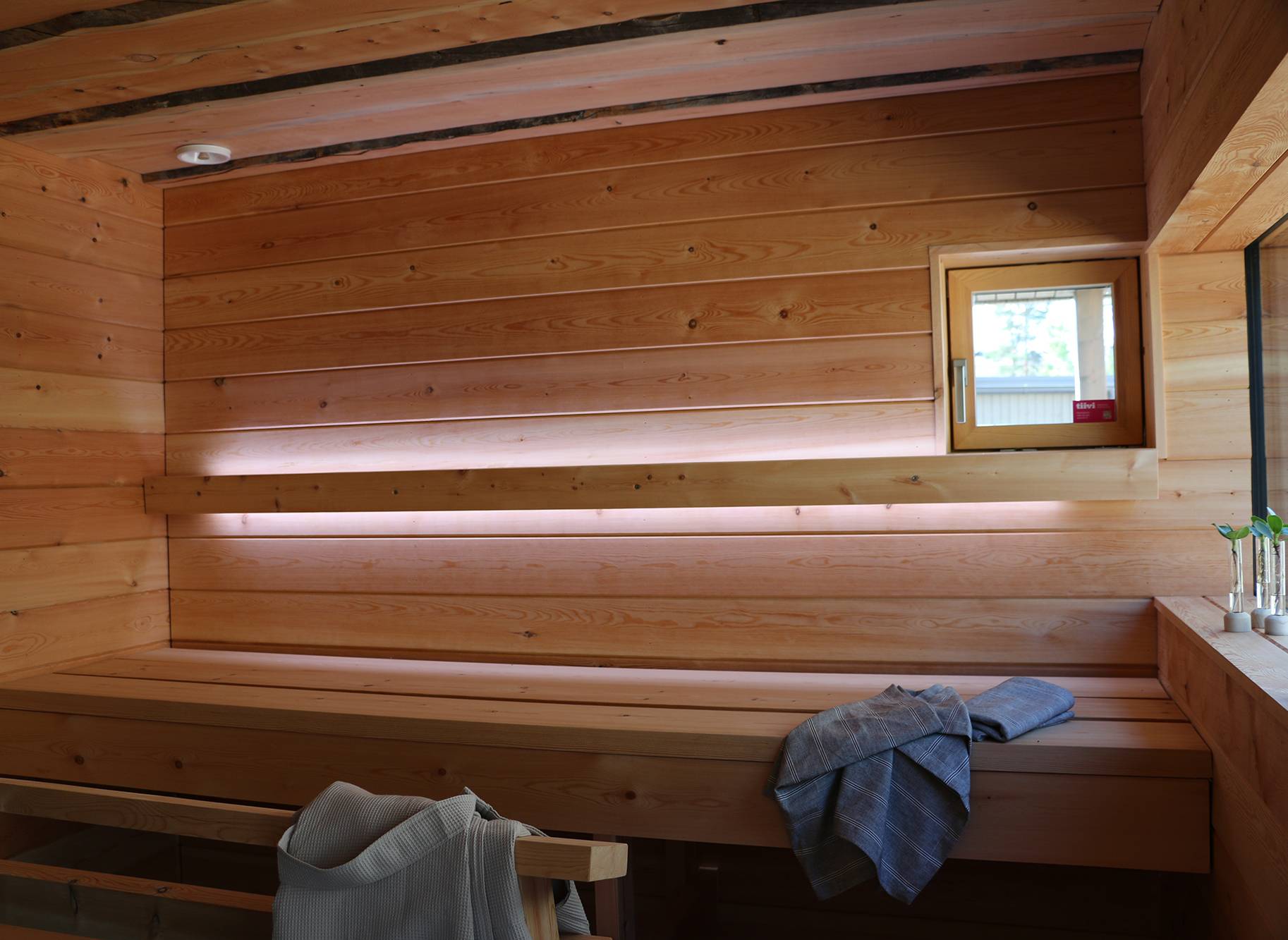 Saunabeleuchtung mit LED-Lichtleisten an der Rückenlehne. Die Led-Streifen leuchten nach oben und nach unten. Ledstore.fi