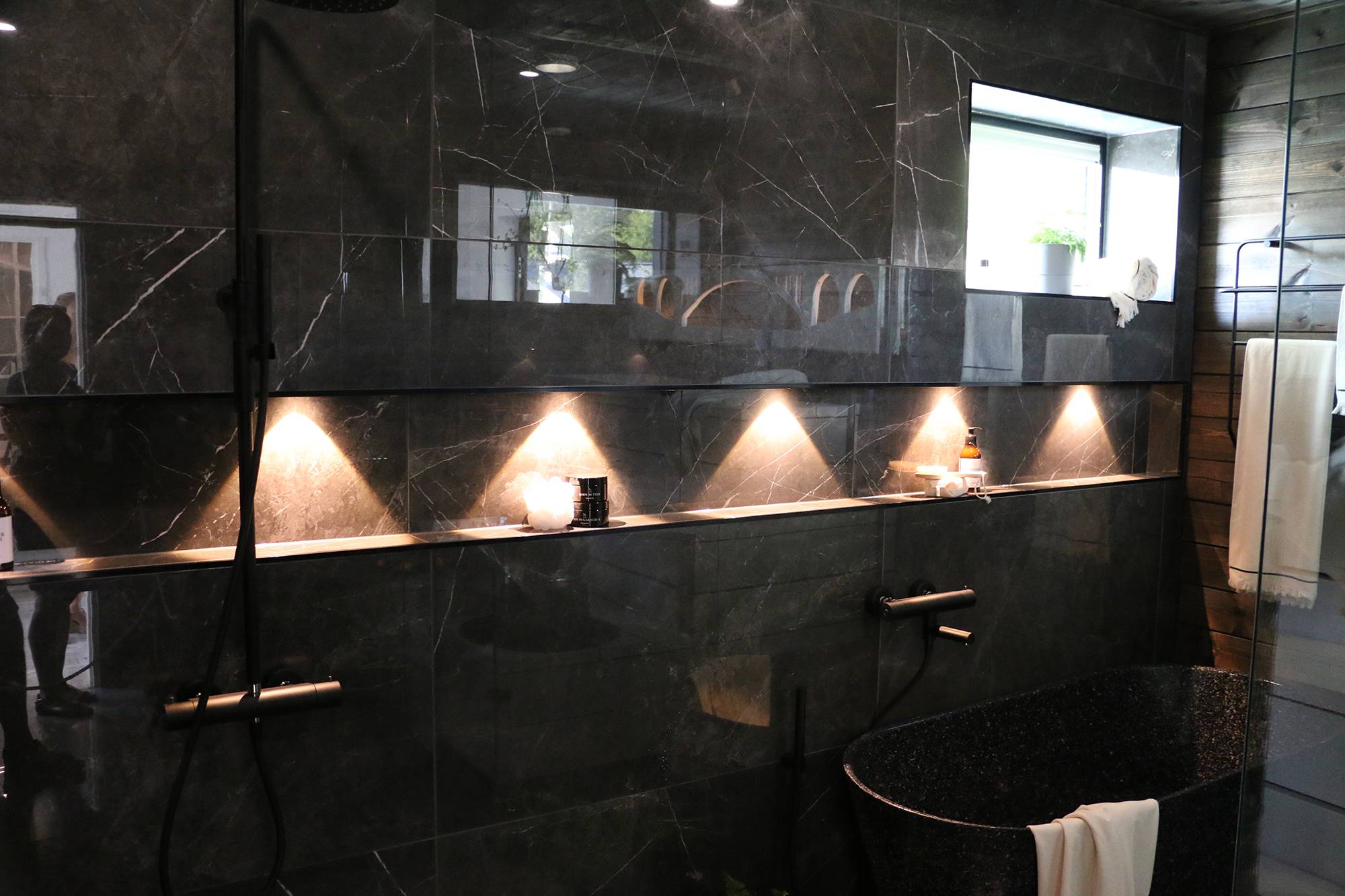 Im Badezimmer beleuchten Strahler das Shampooregal. Ledstore.fi