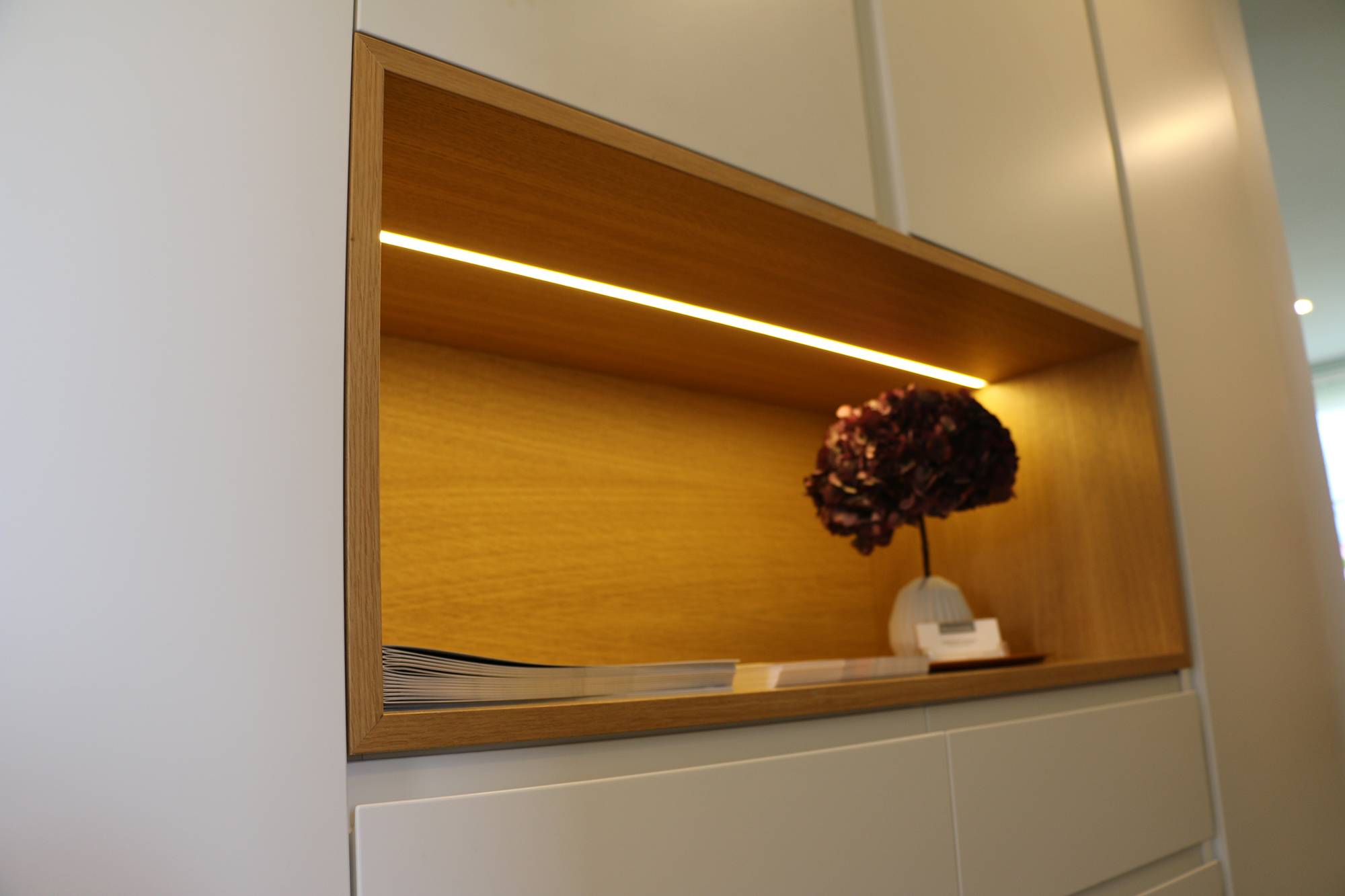 LED-Leuchtband auf dem Regal eines Schranks in einem flächenbündigen Profil montiert. Die Beleuchtung ist stimmungsvoll und hebt ein schönes Detail hervor. Ledstore.fi