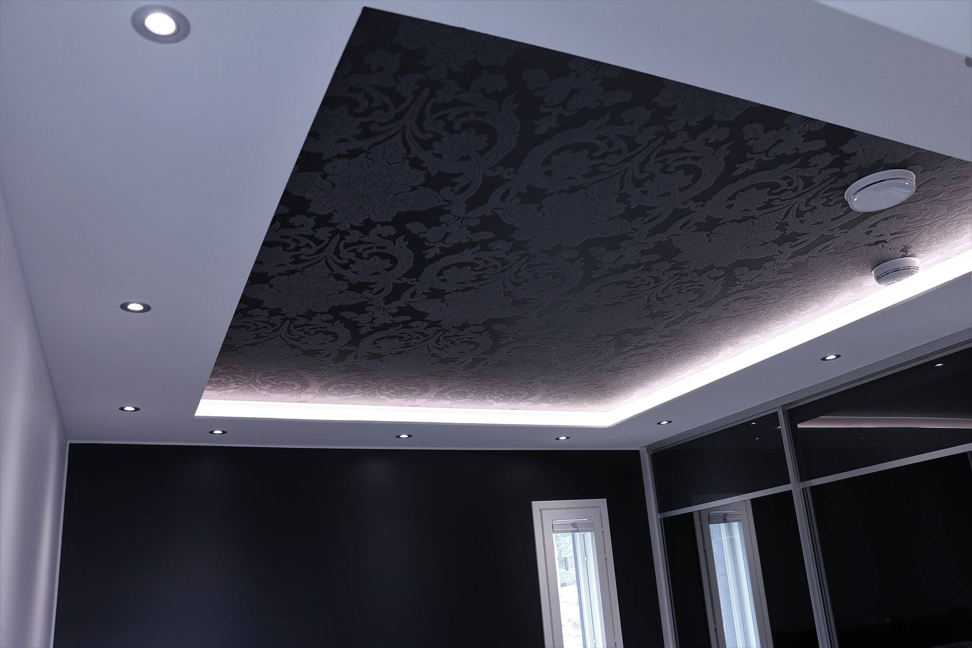 Eindrucksvolle Beleuchtung im Schlafzimmer. In die untere Decke eingelassene Strahler und eine LED-Leiste über der unteren Decke, die indirekt durch die Decke leuchtet. Ledstore.fi