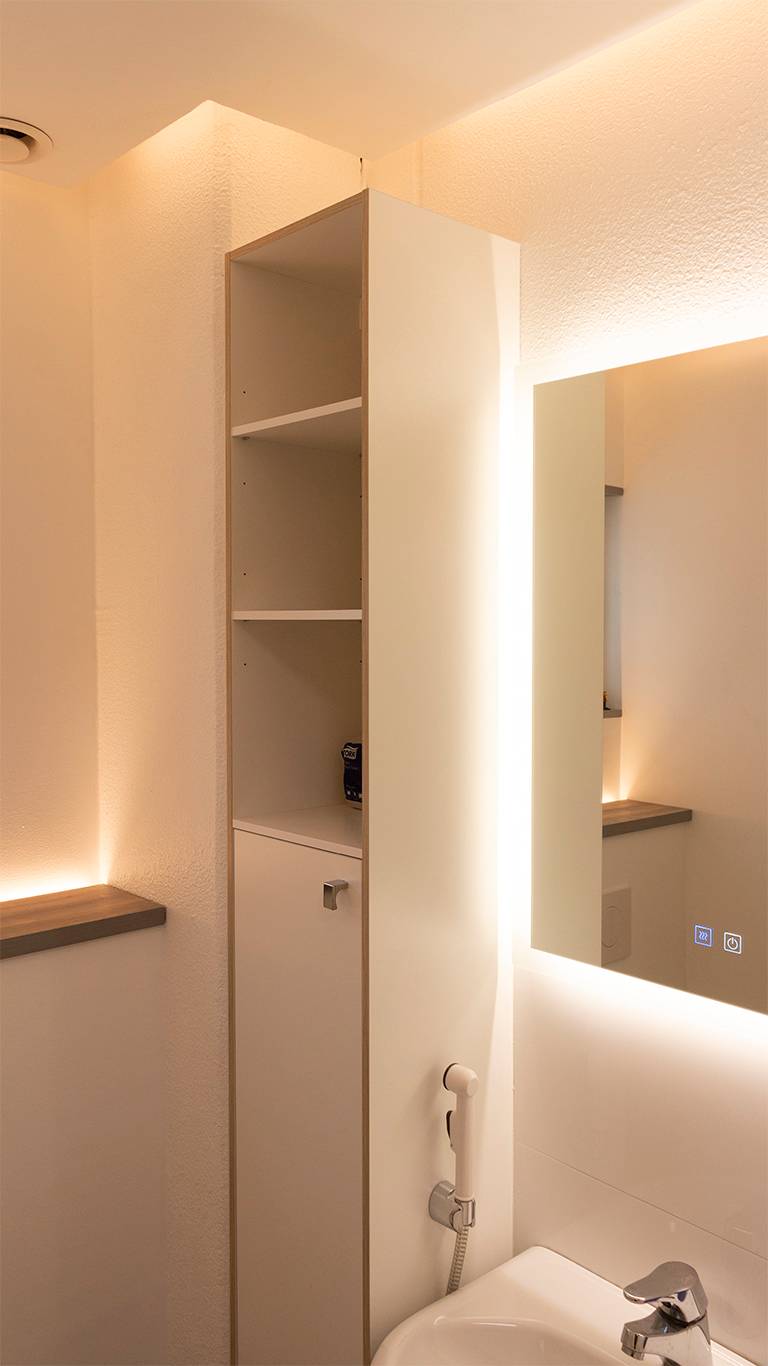 Indirektes Licht im Badezimmer. Ein Lichtspiegel kombiniert mit indirektem Licht von der Decke und einem nach oben gerichteten LED-Band hinter der Toilettenkabine. Ledstore.fi