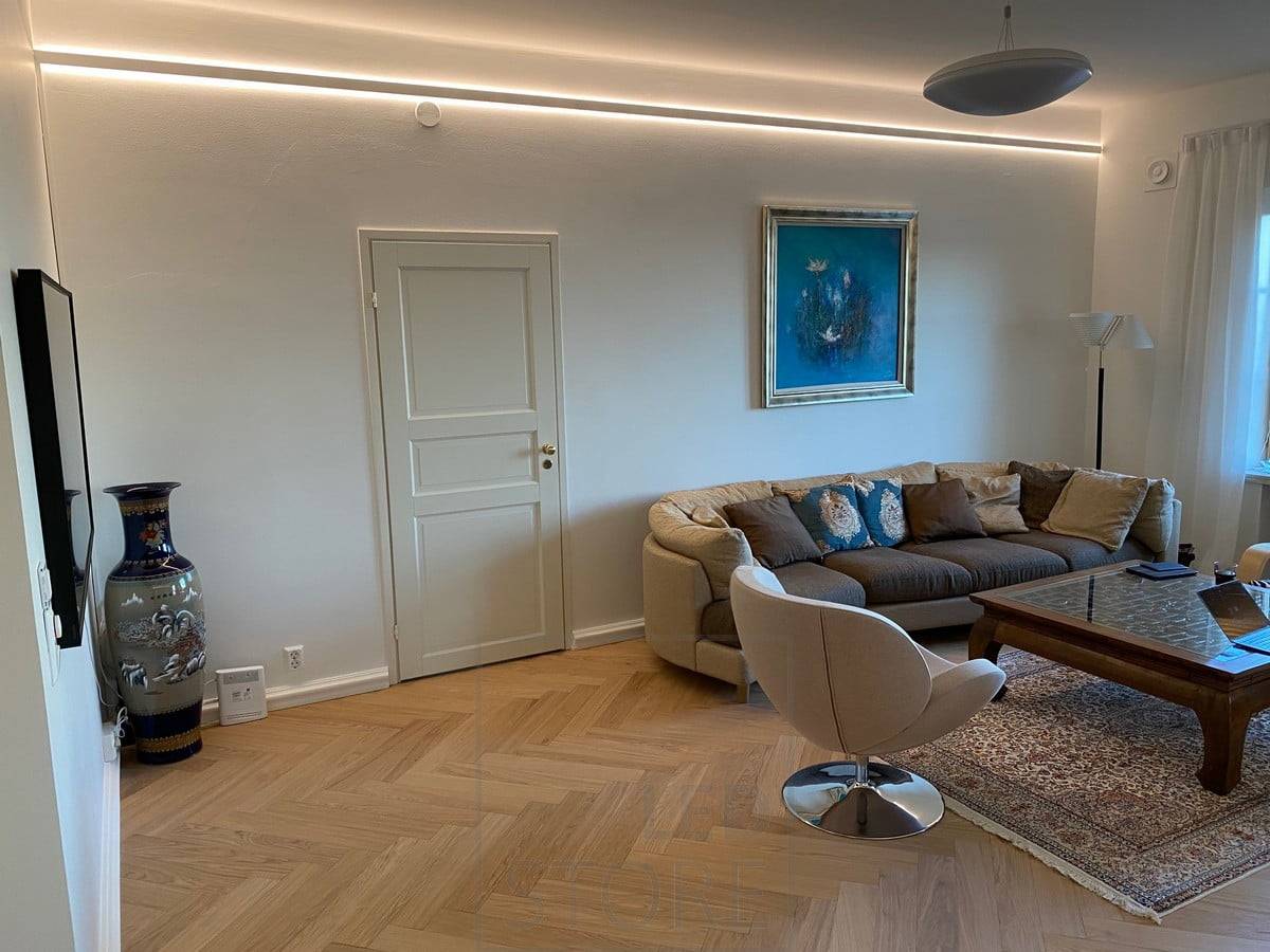 Ein in zwei Richtungen beleuchtetes Aluminiumprofil, das leicht von der Decke herabhängt. Led-Streifen beleuchten den gesamten Raum mit indirektem Licht. Ledstore.fi