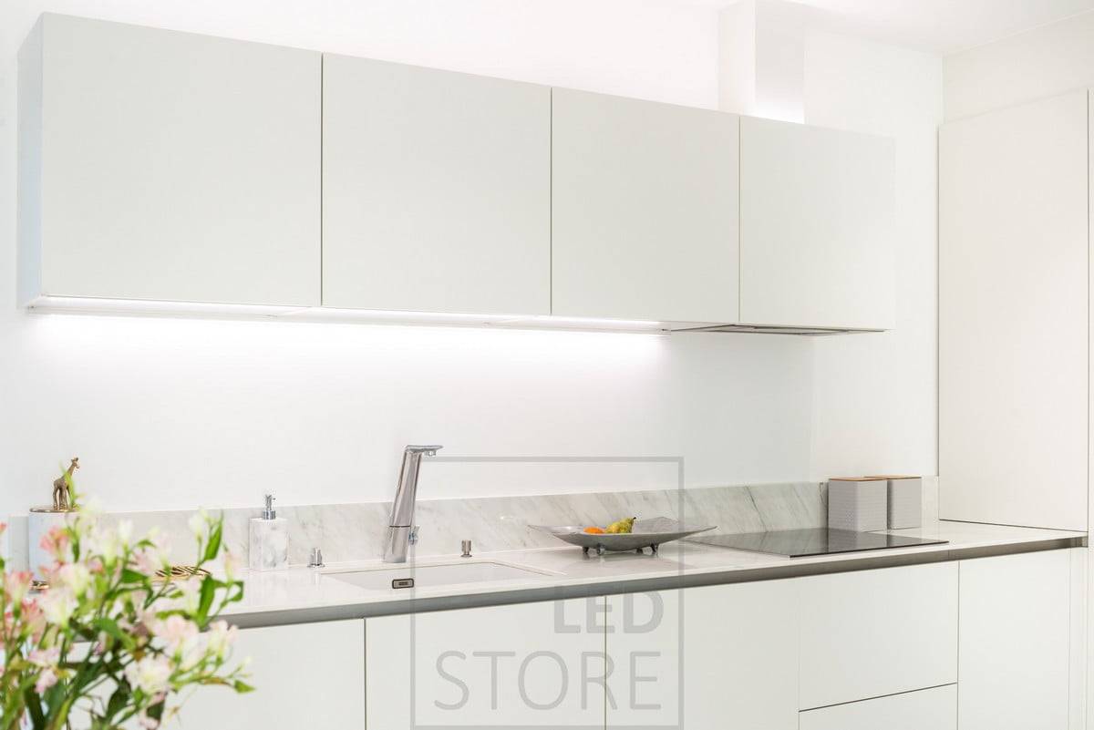 LED-Leisten beleuchten die Oberseite der Schränke und die Arbeitsplatte. Das neutrale Licht unterstreicht die klaren Töne der weißen Küche. Ledstore.fi