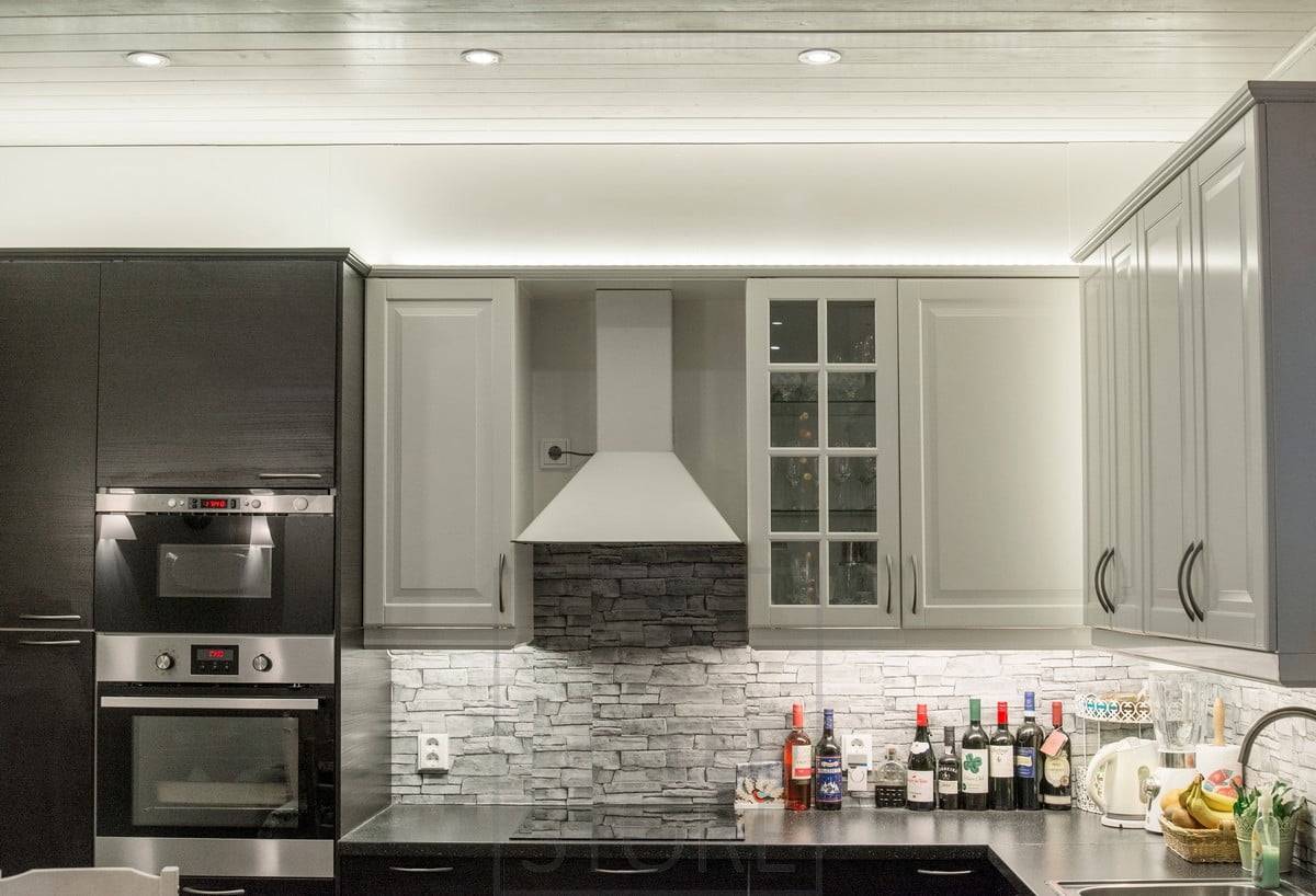 In der Küche, über den Schränken, beleuchten LED-Streifen indirekt nach oben, das Licht geht durch die Decke. Strahler als Allgemeinbeleuchtung. Die Etage wird von einer LED-Leiste beleuchtet, die an der Basis der oberen Schränke angebracht ist. Ledstore.fi