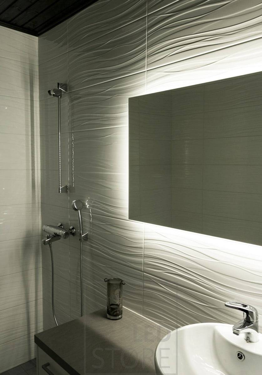 HALO, ein großer rechteckiger Lichtspiegel, leuchtet durch die Wand hindurch, hebt die strukturierten Fliesen hervor und verleiht dem Badezimmer Atmosphäre. Ledstore.fi