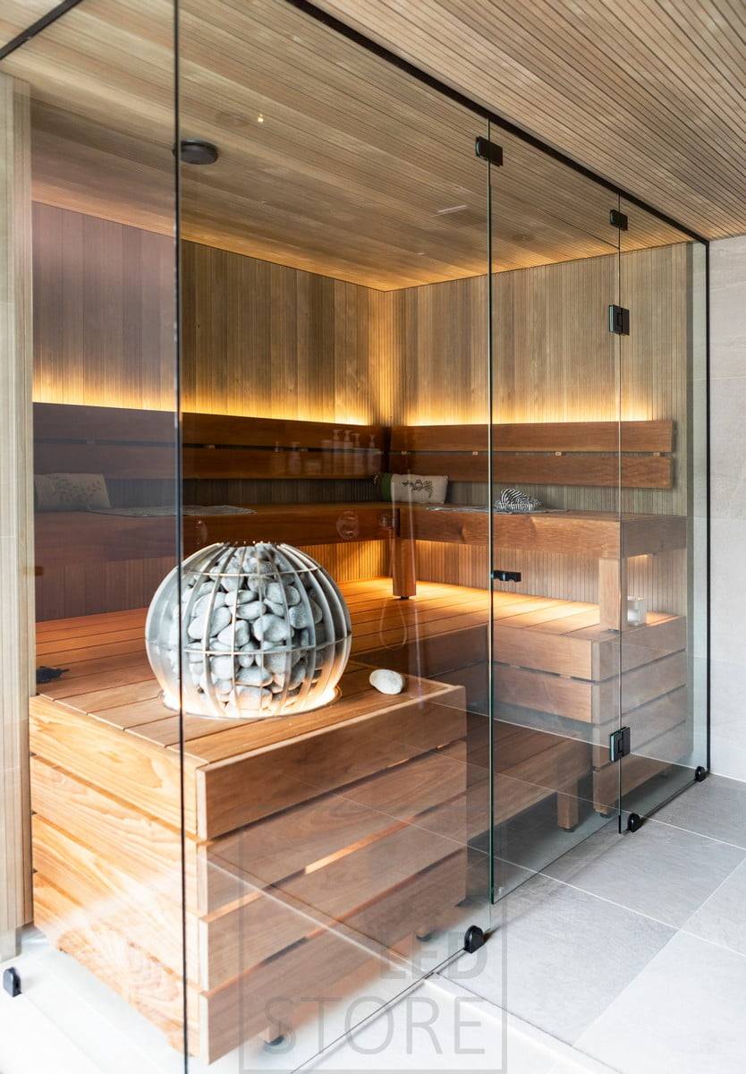 Ambiente-Beleuchtung für die Sauna durch indirektes Licht, wobei die LED-Leiste an der Rückenlehne nach oben und unter der Bank nach unten gerichtet ist. Ledstore.fi