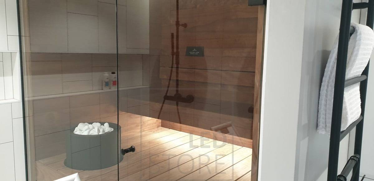 Das Led-Band unter dem Kondenswasser beleuchtet die Sauna mit indirektem Licht. Die Beleuchtung im Waschraum reicht dank der Glaswand auch in die Sauna hinein. Ledstore.fi