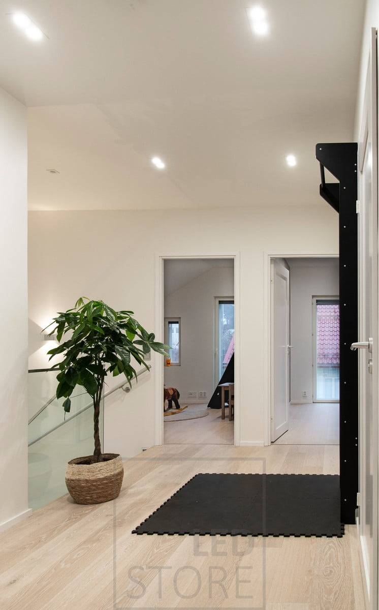 Allgemeinbeleuchtung mit Led-Spots von TUPLAKANTTI an der Decke und einer bidirektionalen Wandleuchte an der Wand, um ein stimmungsvolles Licht im Treppenhaus zu schaffen. Ledstore.fi