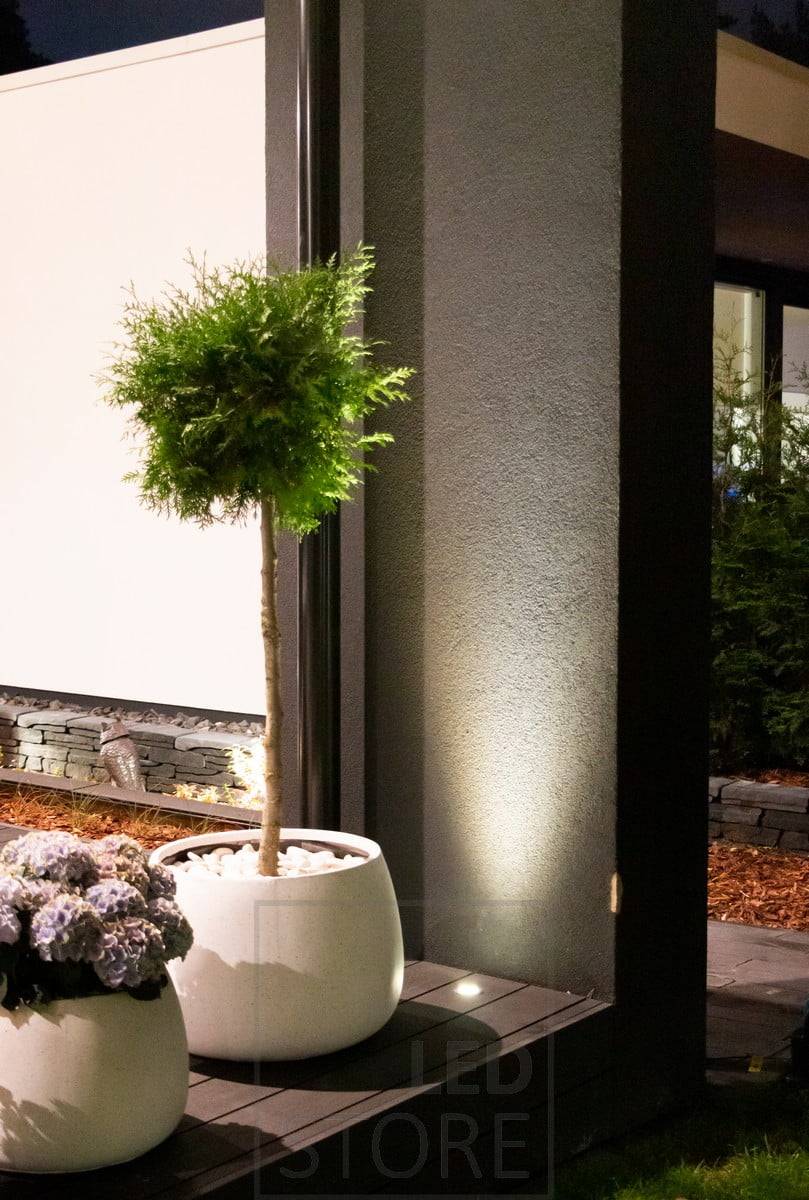 Ein nach oben leuchtender Strahler, der in einen Terrazzo eingebettet ist, nutzt die Wand als reflektierende Oberfläche. Das Licht hebt auch die Pflanze im Vordergrund schön hervor. Ledstore.fi