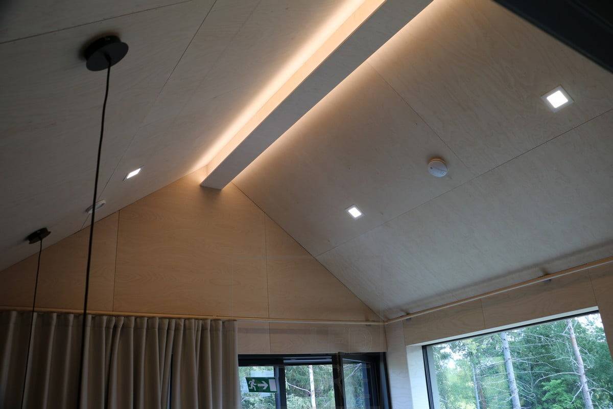 Led-Leisten an einer schrägen Decke, um das Deckenmuster zu akzentuieren und eine stimmungsvolle Beleuchtung zu schaffen. Die Allgemeinbeleuchtung wird durch zusätzliche Paneelleuchten gewährleistet. Ledstore.fi