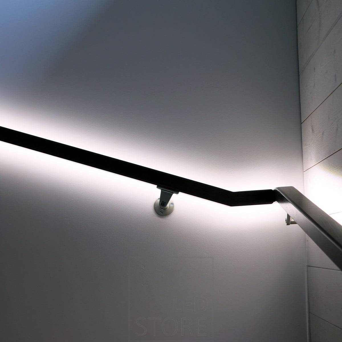 Eine zur Wand gerichtete LED-Leiste an einem Handlauf, die die Wand mit indirektem, weichem Licht beleuchtet. Ledstore.fi