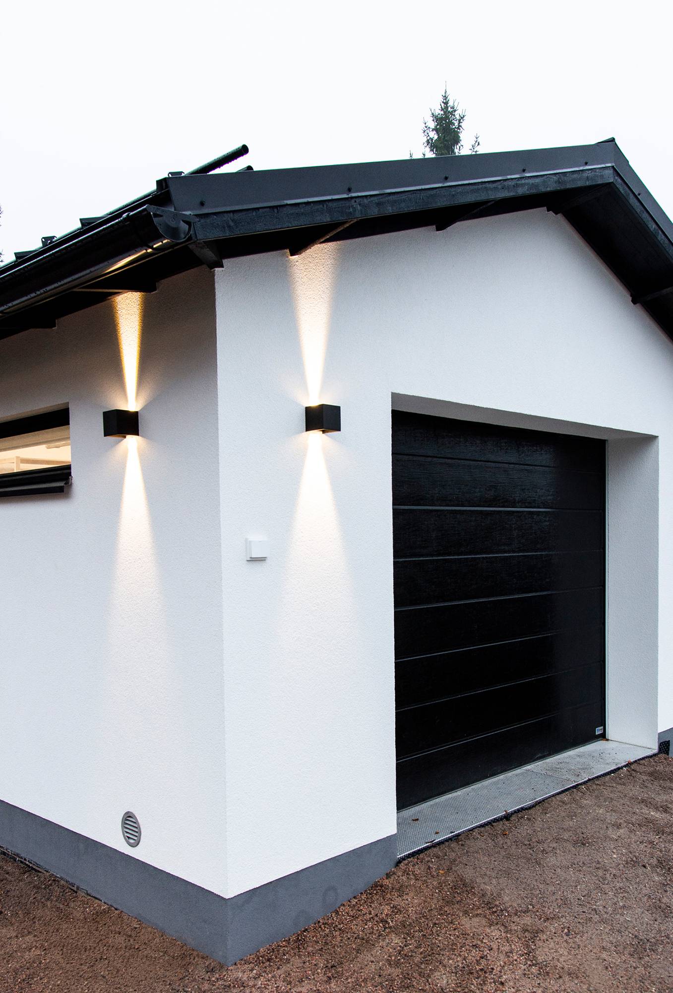 Schwarze bidirektionale FUNK-Wandleuchte für die Garagenfassade. Die dimmbare, schwarze LED-Leuchte FUNK ermöglicht es Ihnen, den Winkel des Lichts mit Hilfe der Flügel an der Leuchte einzustellen. Diese schlichte Leuchte macht sich gut in hohen Räumen, Fluren, Treppenhäusern, Außenwänden und Terrassen. Die Leuchte ist feuchtigkeitsgeschützt nach IP65 und eignet sich sowohl für den Innen- als auch für den Außenbereich. Auch in Weiß erhältlich. Ledstore.fi