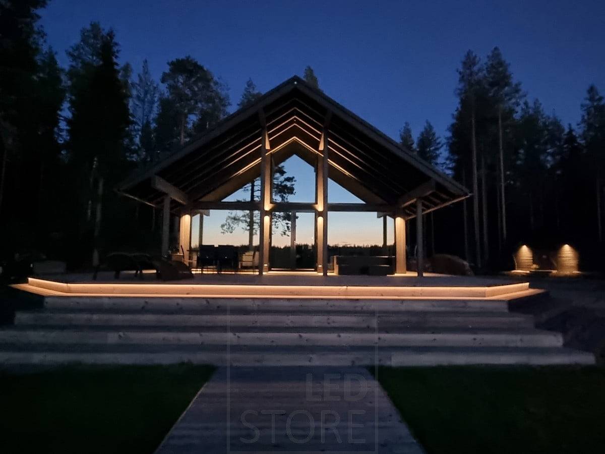 Vielseitige Außenbeleuchtung mit LED-Streifen an der Treppe und Wandleuchten. Die Wandleuchten leuchten an einem hohen Punkt in zwei Richtungen und an einem niedrigeren Punkt in eine Richtung. Ledstore.fi