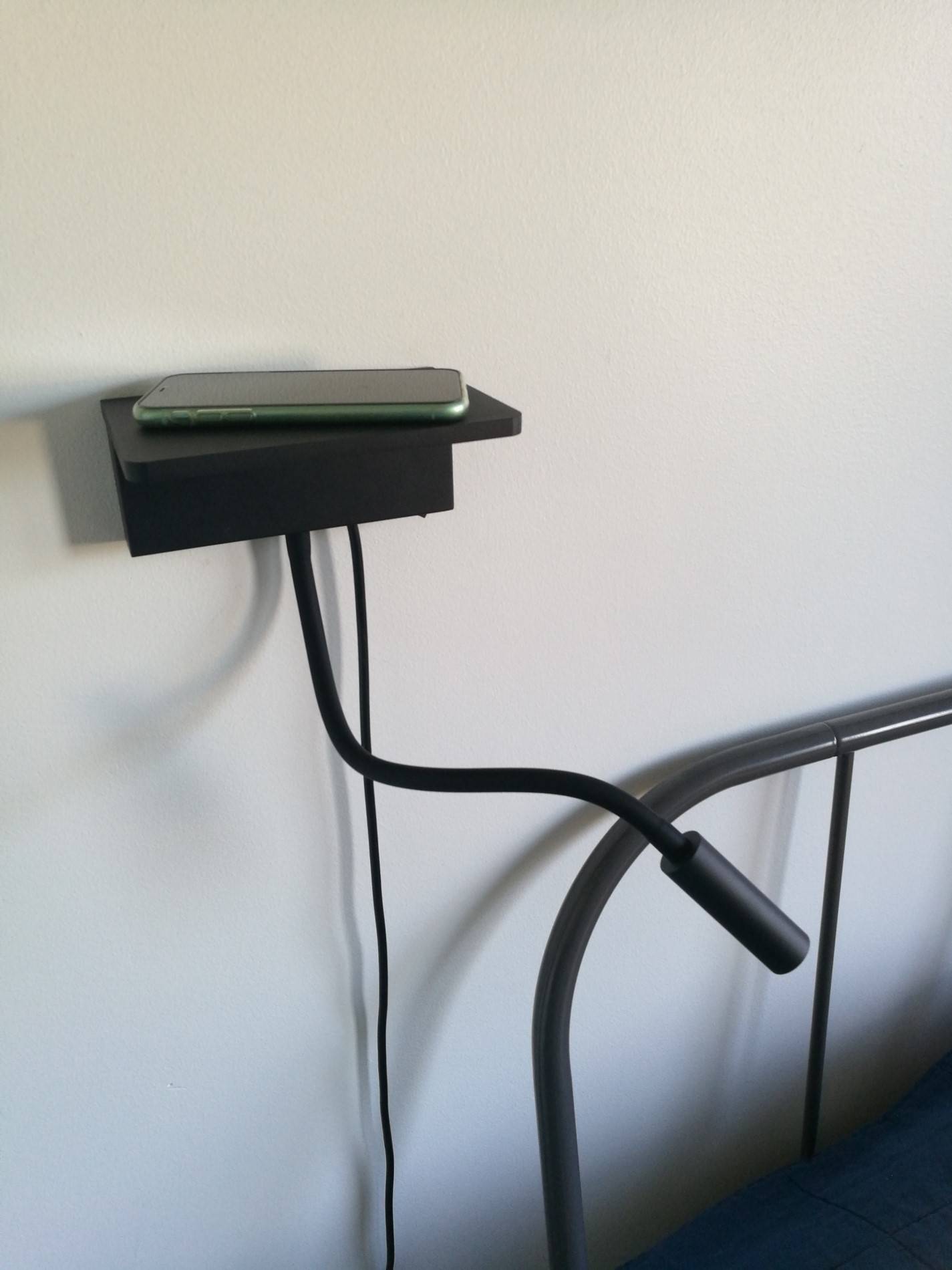 NIGHT BLADE an der Wand montiert, mit einem Telefon auf der Ladestation.