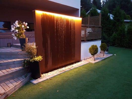 Ein modernes Wasserspiel für den Garten, mit einem LED-Streifen an der Spitze, der nach unten leuchtet.