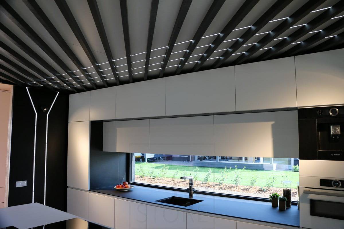 Led-Leiste in schwarzem Profil, unter den Balken. Die Led-Profile beleuchten die Küche und dienen gleichzeitig als dekoratives Element.  