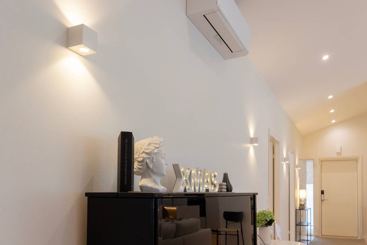 Ein modernes Wohnzimmer mit stilvollen Wandleuchten von LedStore.fi, schwarzen Schränken, Wohnaccessoires und einer wandmontierten Klimaanlage - eines unserer neuesten 2025 Referenzprojekte.