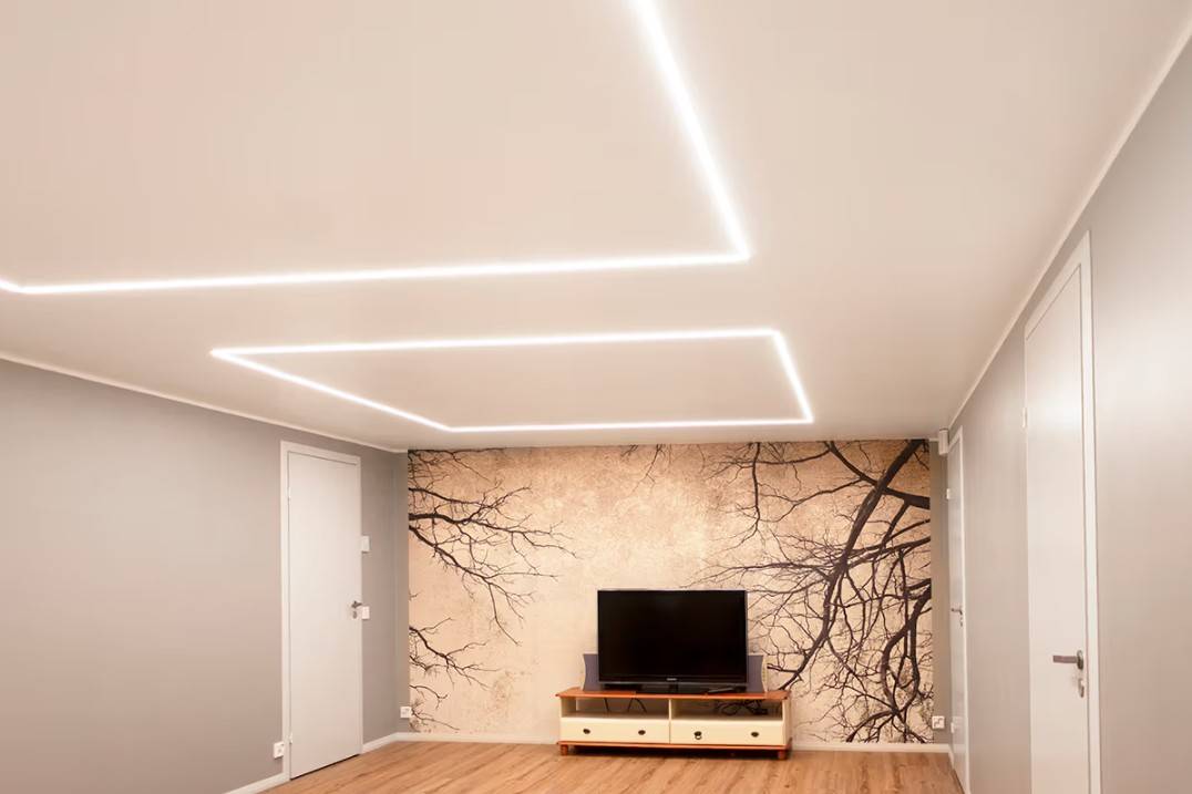 Ein minimalistisches Wohnzimmer in einem Einfamilienhaus in Kaitamäki, Espoo, in dem LED-Deckenleuchten von LedStore.fi ein stilvolles Beleuchtungskonzept schaffen. Das Wohnzimmer verfügt über einen Fernsehtisch und ein auffälliges Wandgemälde, das durch hochwertige LED-Beleuchtung akzentuiert wird. 