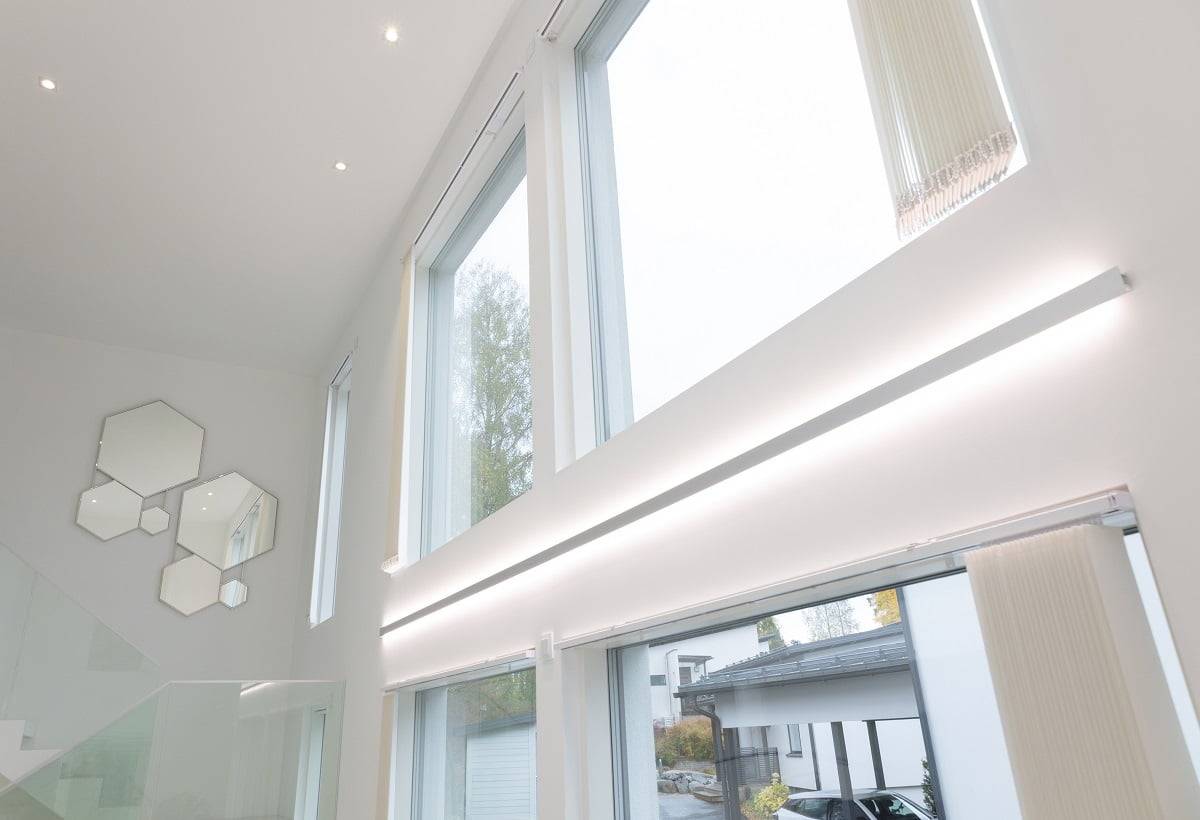 LedStore Innenbeleuchtung - eine vom Licht geprägte Atmosphäre LedStore.fi Online-Shop Produktbeschreibung: Das moderne Interieur besticht durch große und hohe Fenster, die mit stilvoller LED-Beleuchtung versehen sind. Diese Beleuchtung lässt natürliches Licht hereinströmen. An den weißen Wänden sind in der Nähe der Treppe, die eine Glasbalustrade hat, sechseckige Spiegel kunstvoll angeordnet. Draußen ist die Auffahrt mit geparkten Autos gesäumt, die den modernen Stil vervollständigen.