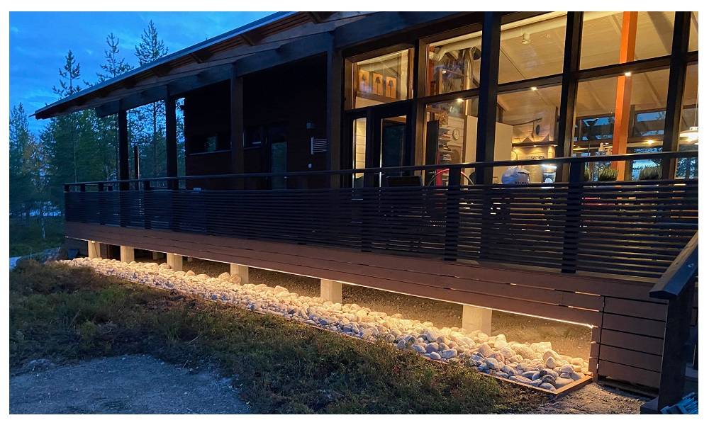 Beleuchtetes LED-Band auf dem Terrassensockel in der Abenddämmerung.
