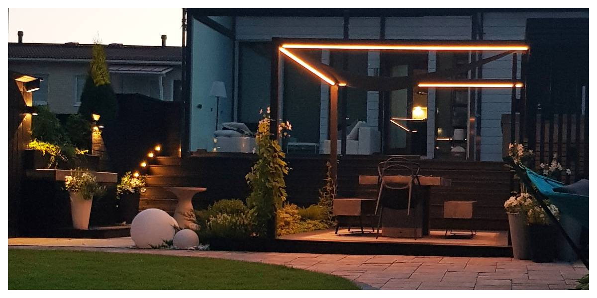 Moderne Hinterhof-Terrasse mit Pergola und stimmungsvoller LED-Beleuchtung. Holzstufen und stimmungsvolle Topfpflanzen. Im Innenhof eines modernen Hauses gelegen, bietet das Ensemble die perfekte Kulisse für Abende im Freien mit hochwertiger LED-Beleuchtung von LedStore.fi.