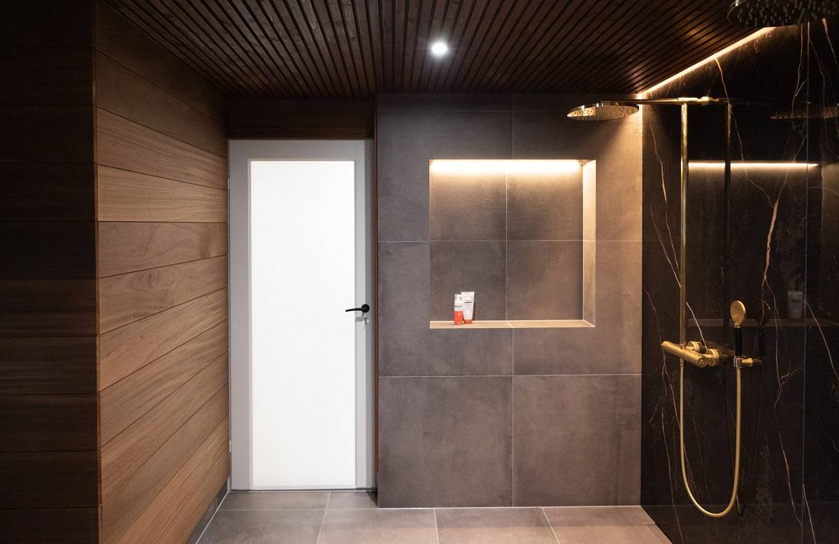 Die Led-Leiste in der Deckenrille und oben auf dem Shampoo-Regal sorgt für eine sanfte Allgemeinbeleuchtung im Badezimmer. Zusätzliche feste, wasserdichte 9W-Strahler. © LedStore.fi  