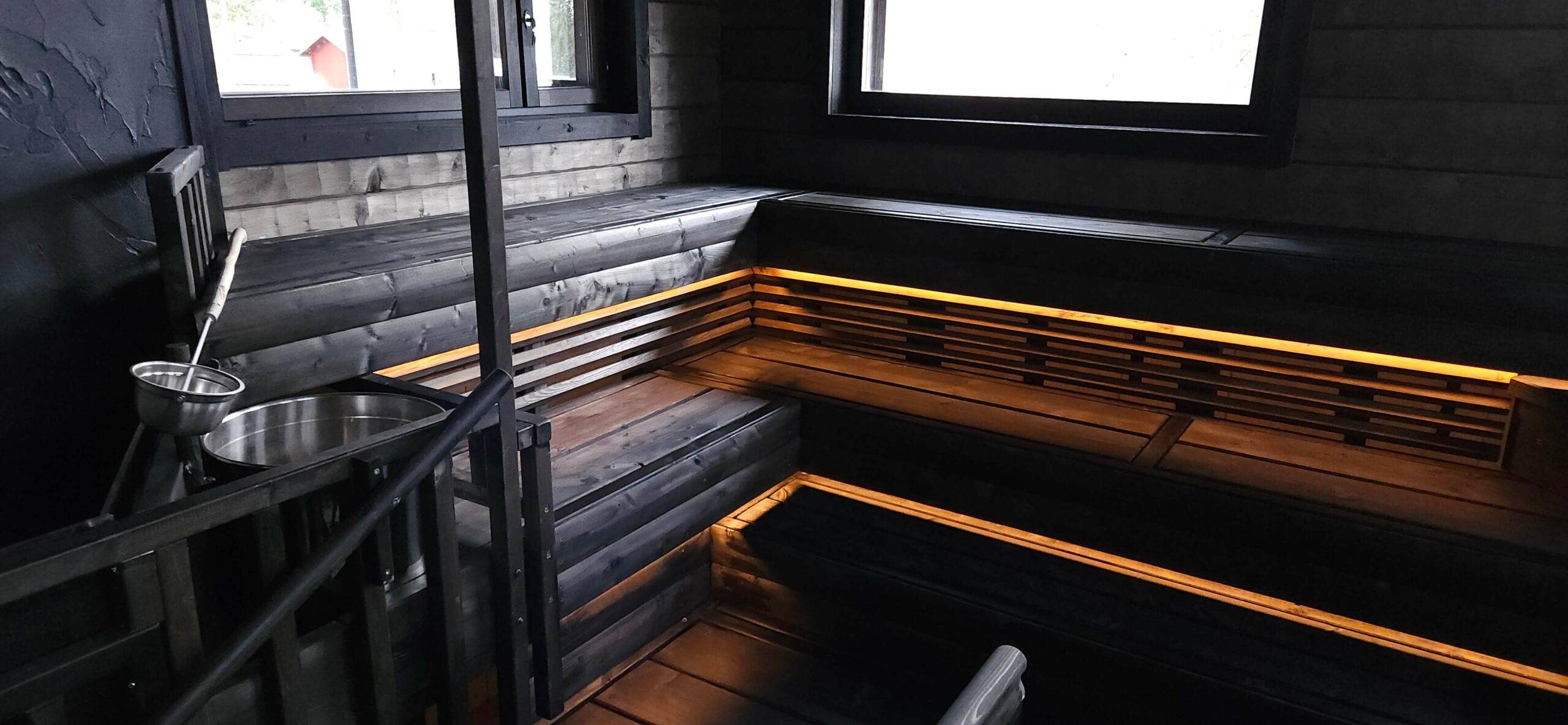 unten an der Decke der dunklen Holzsauna sind warme, gelbliche LED-Lichtstreifen installiert, die nach unten leuchten