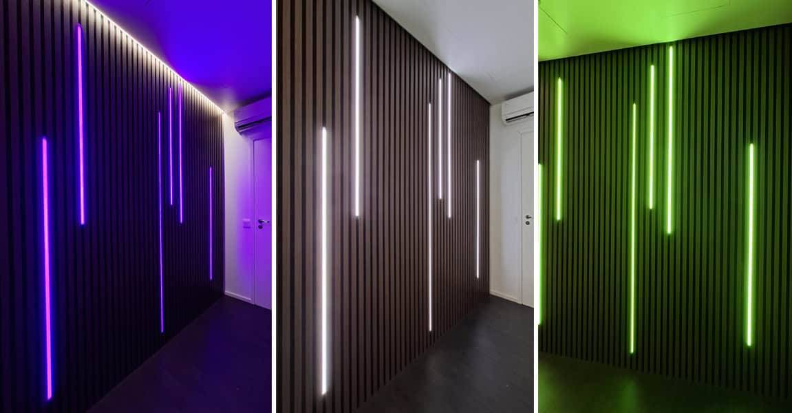 Eine elegant getäfelte dunkle Wand mit blau, weiß und grün leuchtenden LedStore.fi-LEDs.