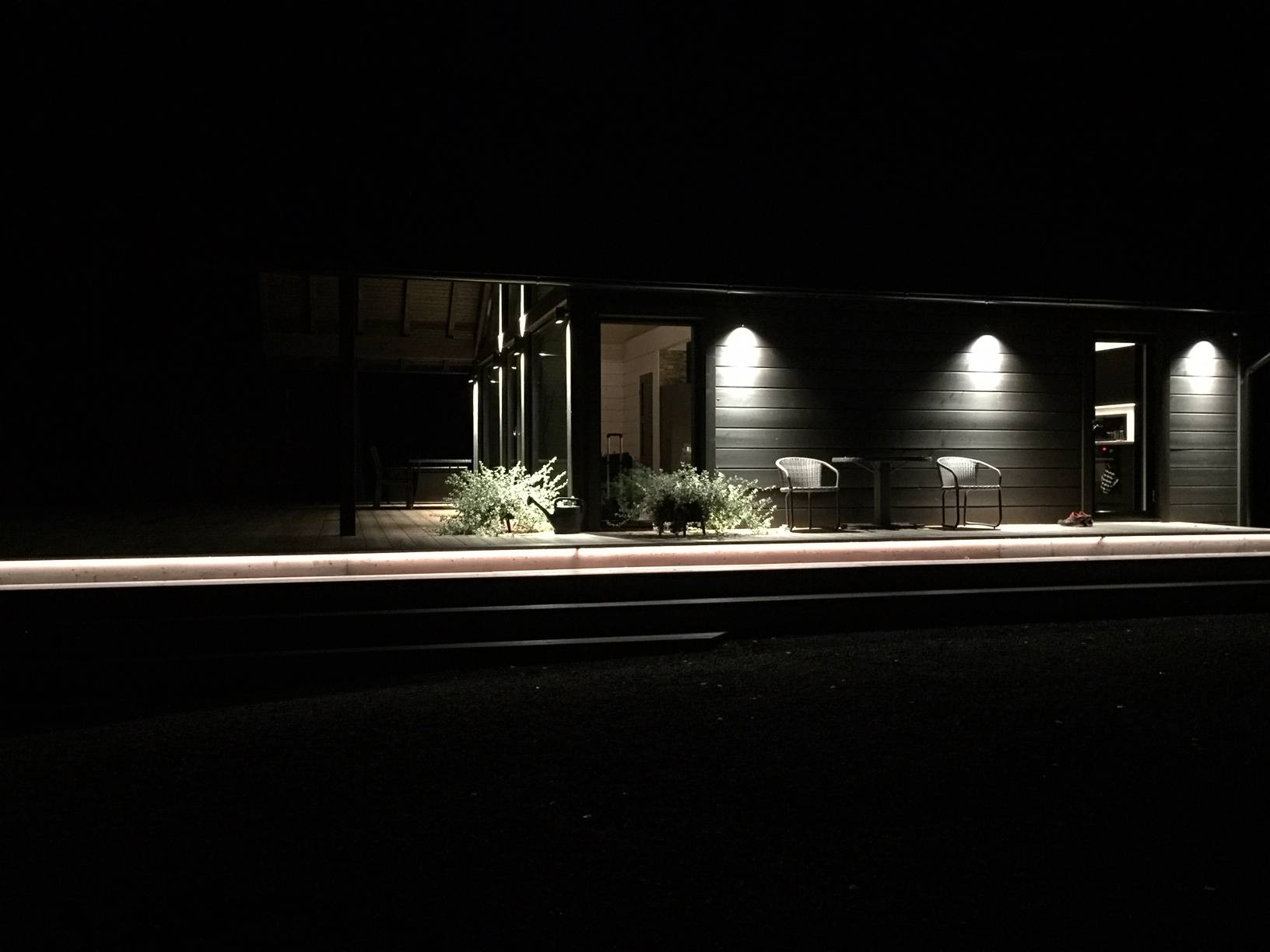 Außenbeleuchtung des Treppenhauses mit LED-Lichtbändern und Wandleuchten, die die hohe Fassade in zwei Richtungen beleuchten. Die untere Seite wird durch einseitige Versionen derselben Leuchte beleuchtet. Ledstore.fi